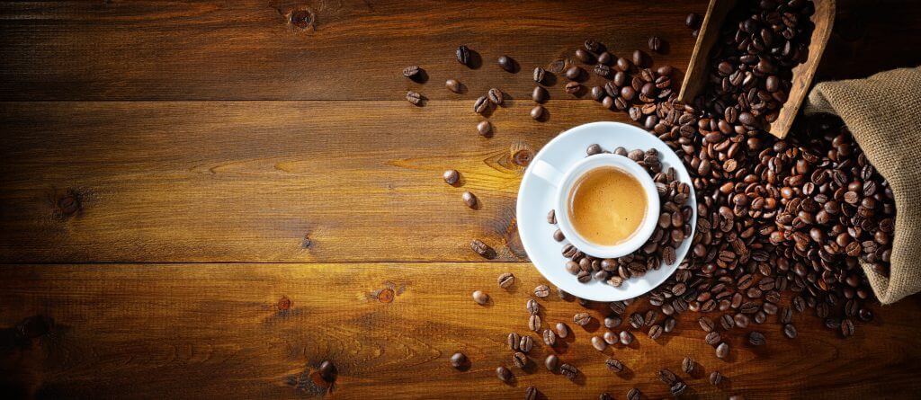 Spilled Coffee Beans Next to a Cup of Coffee